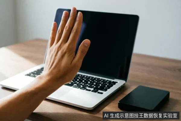 一只手掌在银色笔记本电脑屏幕前做出停止手势,示意拒绝操作或断电。电脑旁放置着一个黑色的外接移动硬盘,桌面环境整洁。画面直观传达出在设备故障时立即停止通电、禁止继续使用的警示含义。
