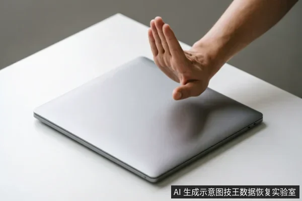 画面展示了一台闭合的银灰色笔记本电脑平放在白色桌面上,一只手掌从右上方伸出,掌心向下对着电脑做出明确的“停止”手势,示意禁止操作或关闭设备。