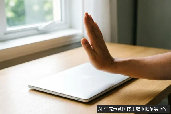 画面展示了一只手在闭合的笔记本电脑上方做出明显的“停止”或“拒绝”手势,手掌张开面向设备。背景为明亮的窗边木桌,光线柔和。该图像直观地传达了在数据恢复过程中保持克制、禁止盲目操作及立即停止通电的核心原则。
