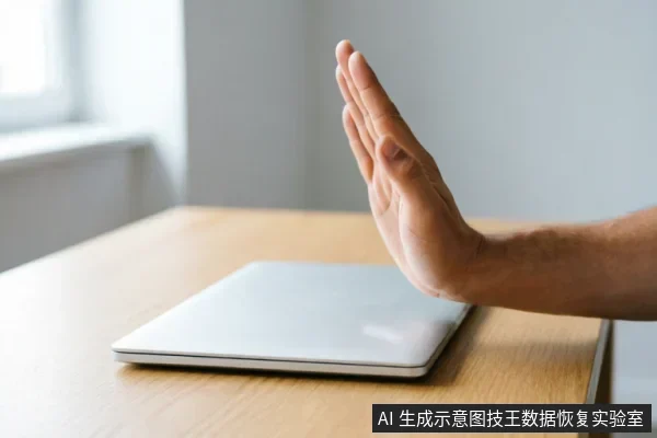 一只手掌在闭合的笔记本电脑前做出明显的“停止”手势，示意紧急制动。画面传达出在电脑硬盘出现识别故障时，应立即断电、禁止反复通电或尝试软件扫描，以保护原始介质数据完整性的核心概念。