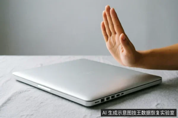 画面展示了一台闭合的银色笔记本电脑平放在桌面上,一只手掌在电脑上方做出明显的“停止”或“拒绝”手势。该动作直观地传达了立即停止操作、切断电源或禁止写入的含义,与数据恢复中保护介质完整性的原则高度契合。