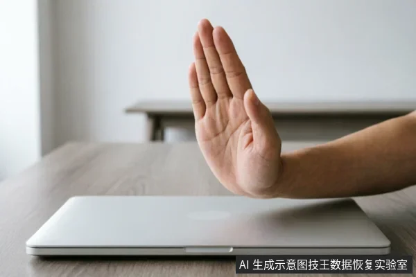 一只手掌在闭合的笔记本电脑前做出明确的停止手势,示意拒绝操作或立即中断。画面主体清晰,无屏幕文字,象征在数据故障时避免误操作、防止数据写入覆盖的紧急止损原则。