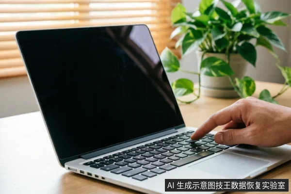 A hand presses a key on a silver laptop keyboard with a black screen, sitting on a wooden desk next to a green potted plant.